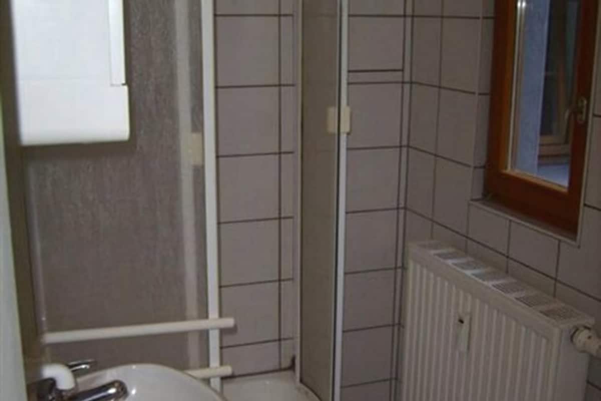 A small bathroom with a white sink, a shower, and a radiator.
