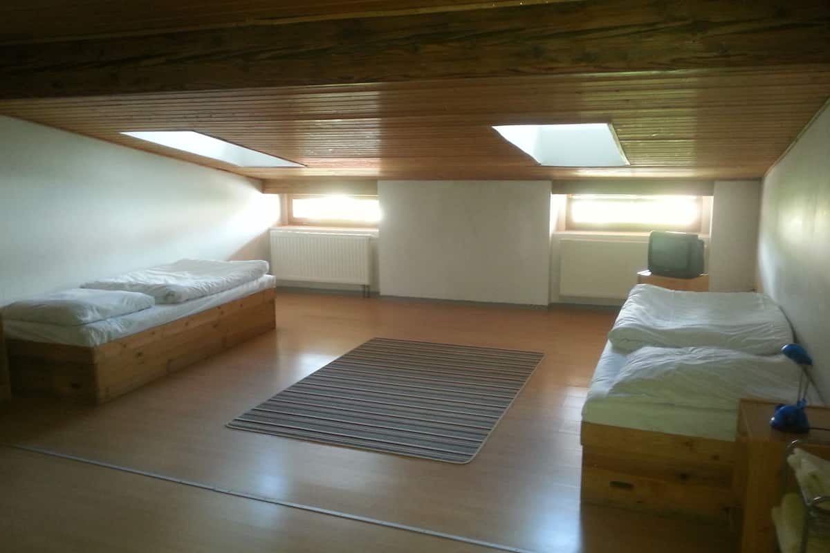 A room with two wooden bunk beds, a small window, and a radiator.