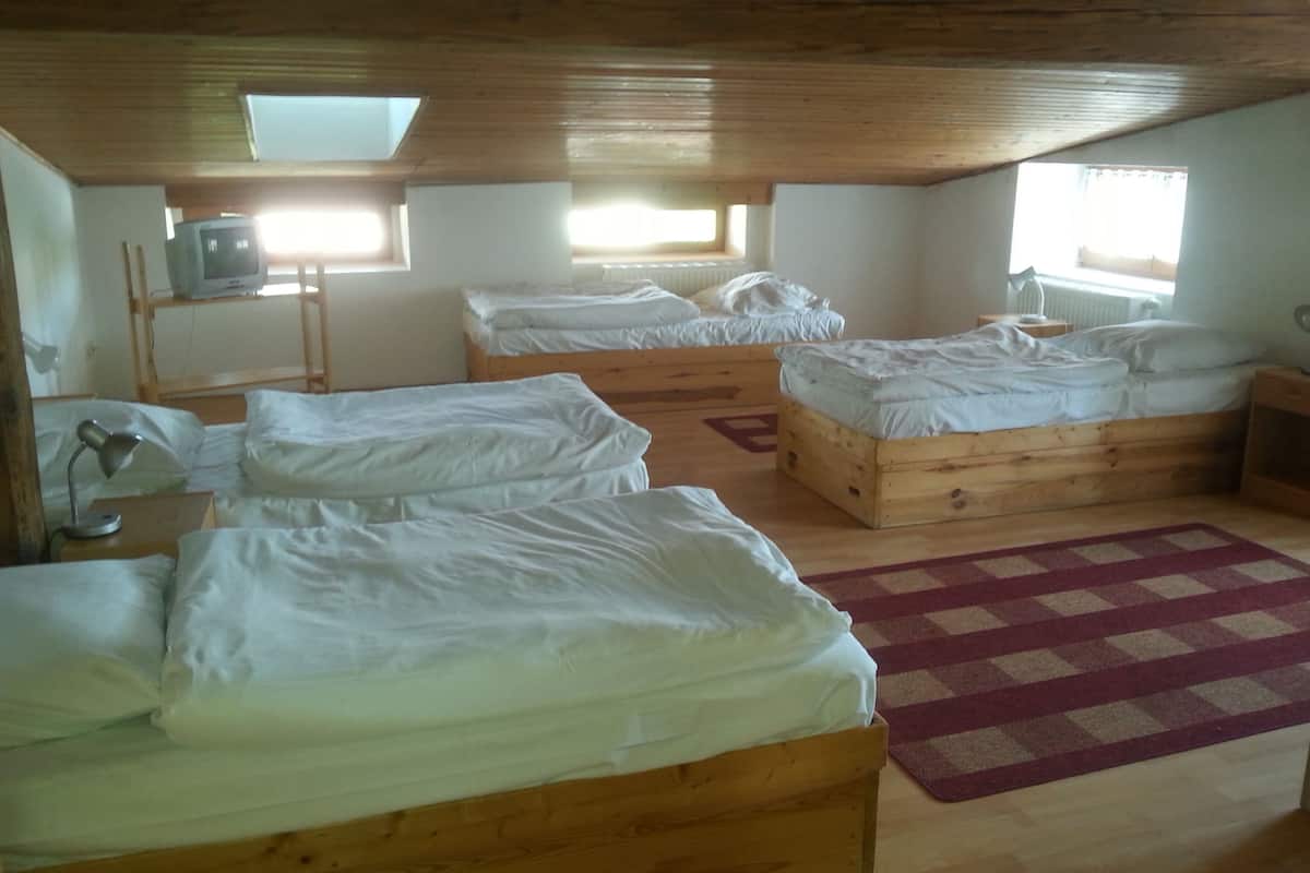 A room with two wooden beds, a desk with a lamp, and a window providing natural light.