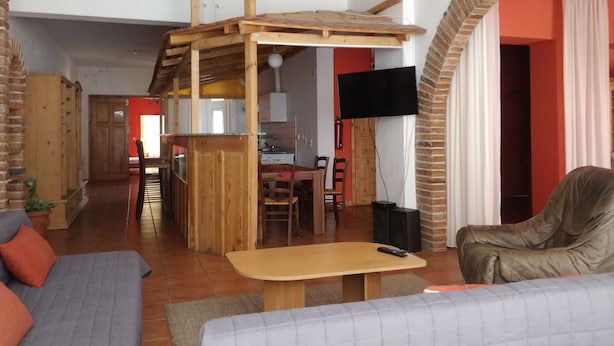 A cozy living room with a wooden loft, a TV mounted on the wall, and a comfortable seating area. - Picobello Pension (Görlitz)