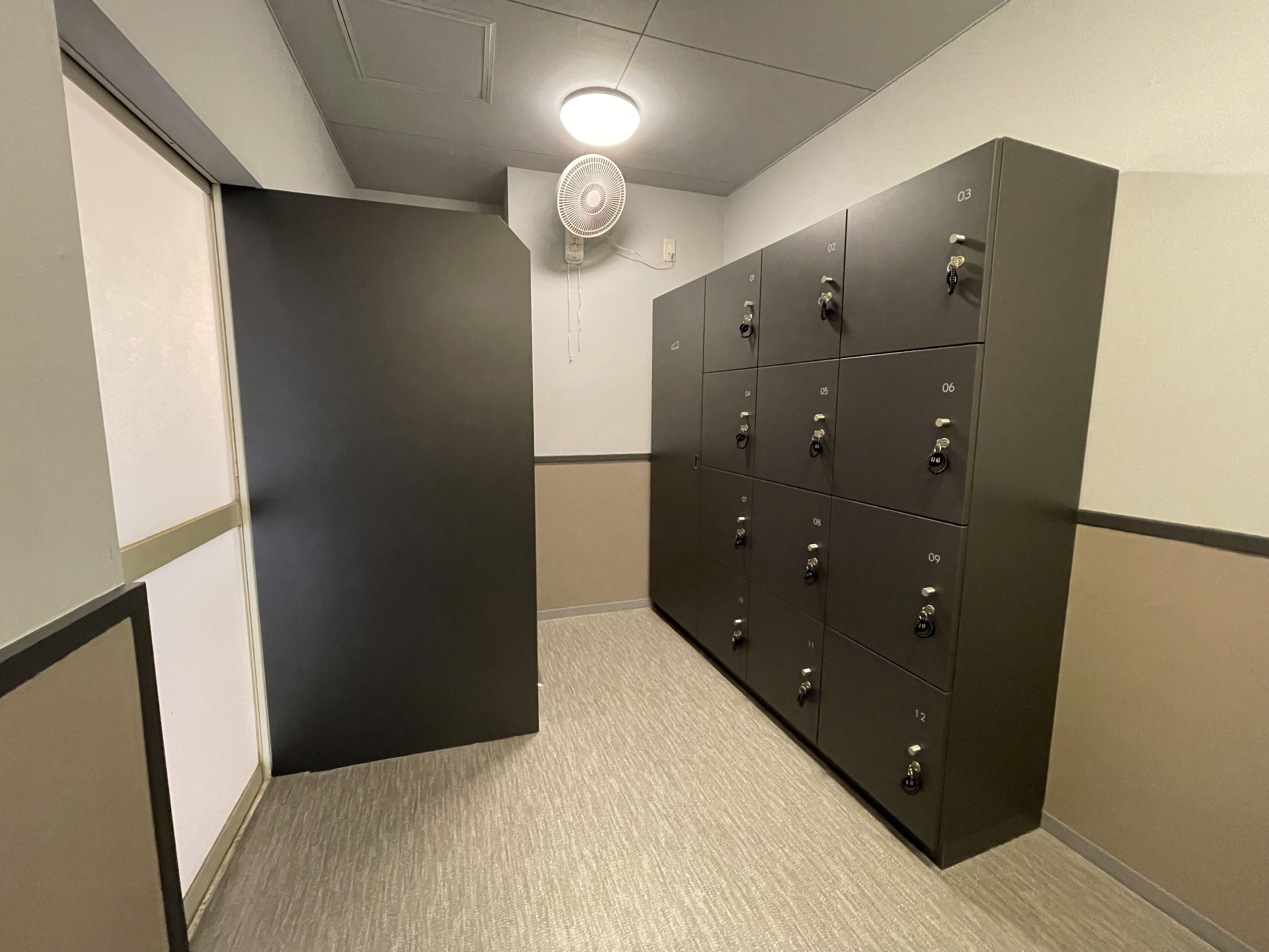 A hallway with lockers, a door, and a ceiling fan.