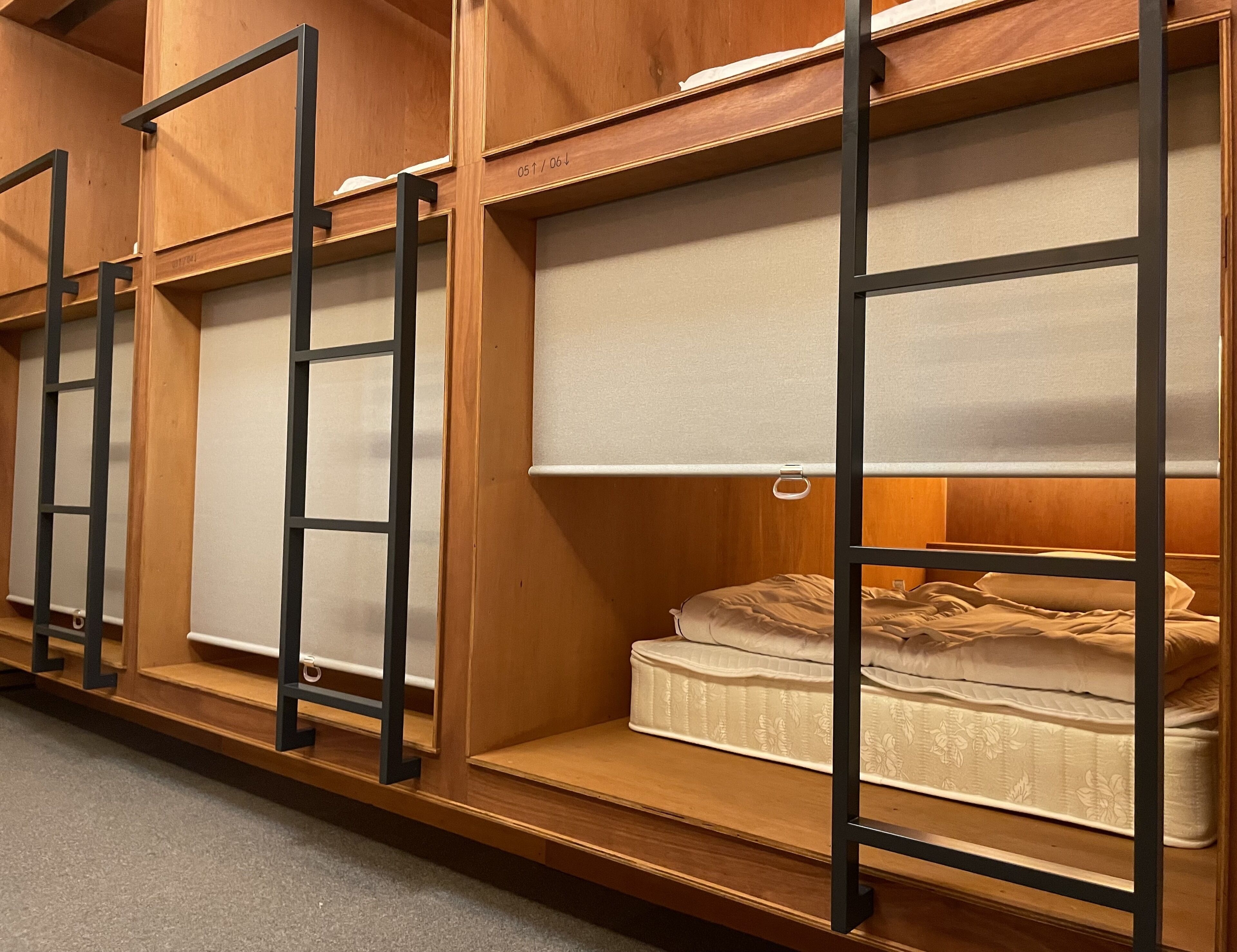 A row of bunk beds with wooden frames and a mattress on the right.