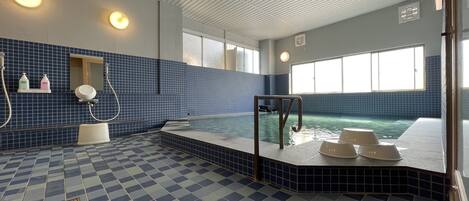 Une piscine avec un sol à carreaux, un petit coin salon et une fenêtre laissant entrer la lumière naturelle.