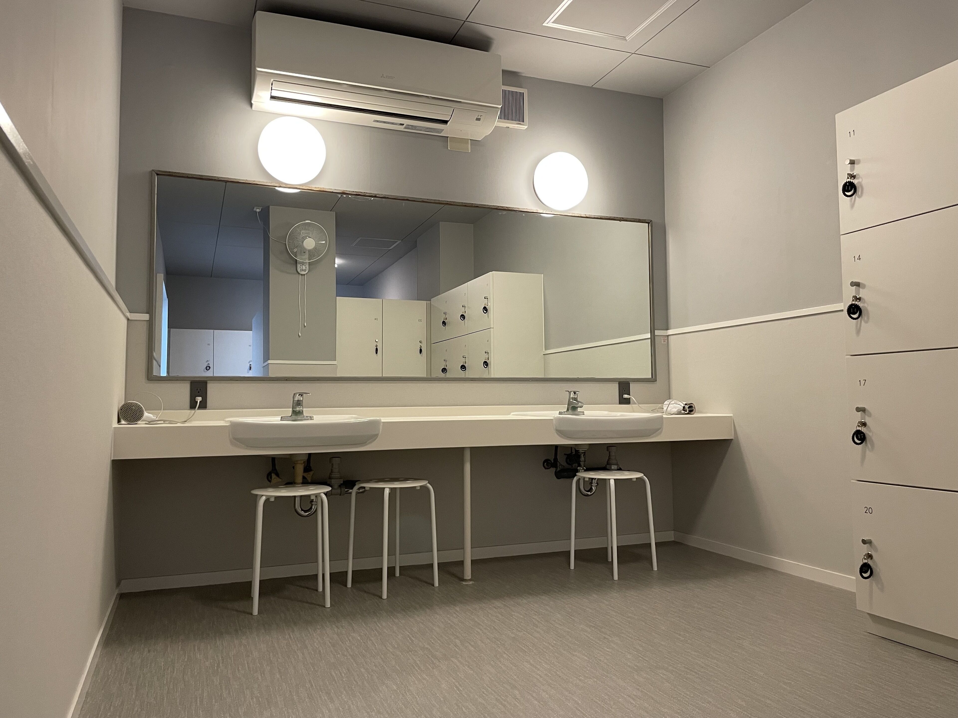 Un baño moderno con dos lavamanos, un espejo grande y un sistema de ventilación.