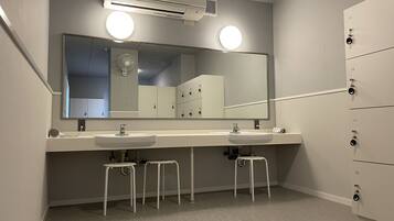Un baño moderno con dos lavamanos, un espejo grande y un sistema de ventilación.