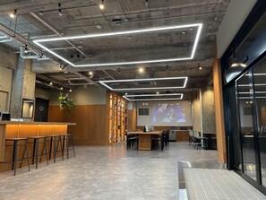 Un interior moderno con barra, asientos y una pantalla de proyección.