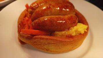 A plate with two sausages, carrots, and pineapple.
