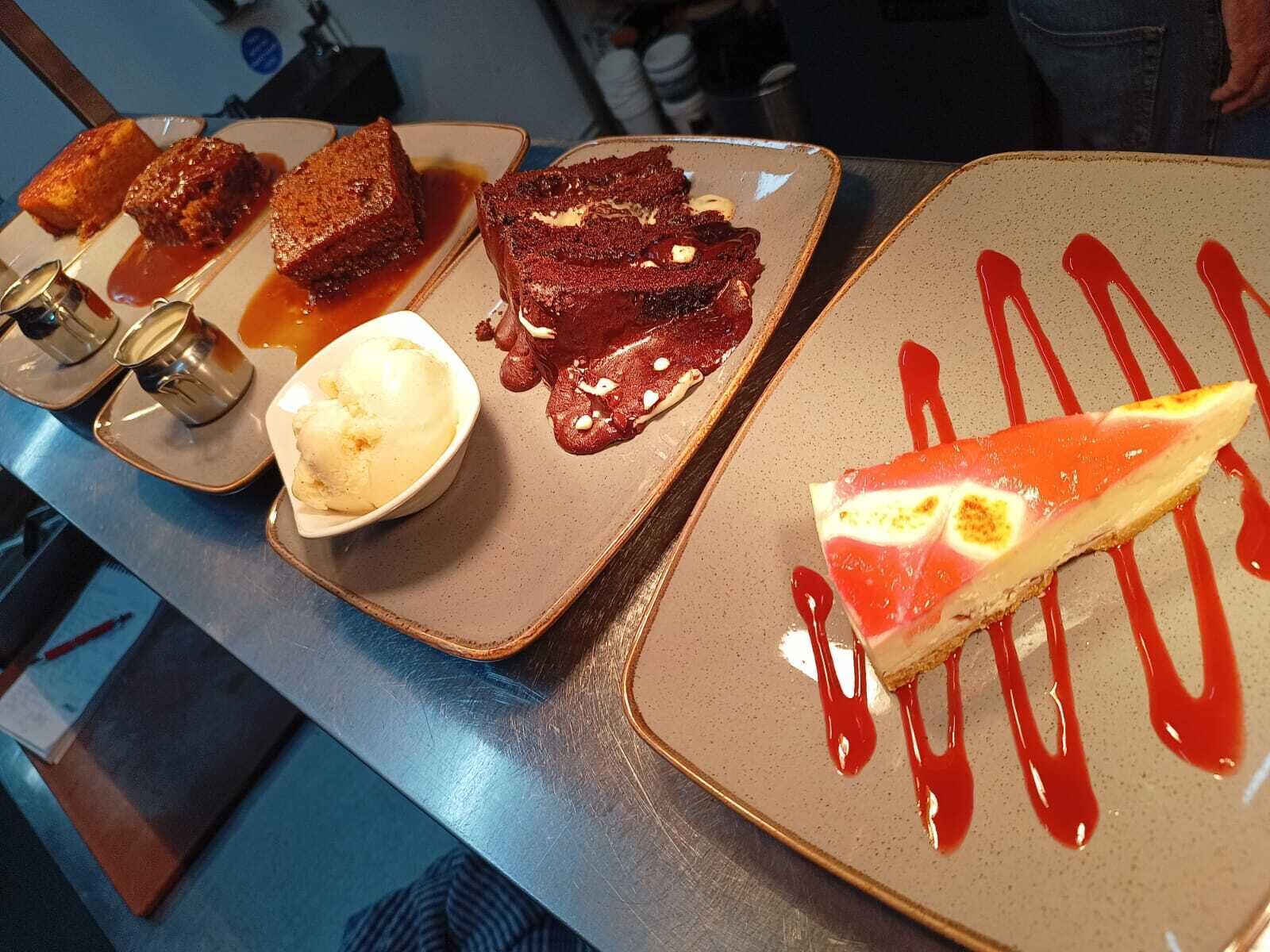 A dessert display with various items including a slice of cheesecake and a scoop of ice cream.