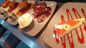 A dessert display with various items including a slice of cheesecake and a scoop of ice cream.