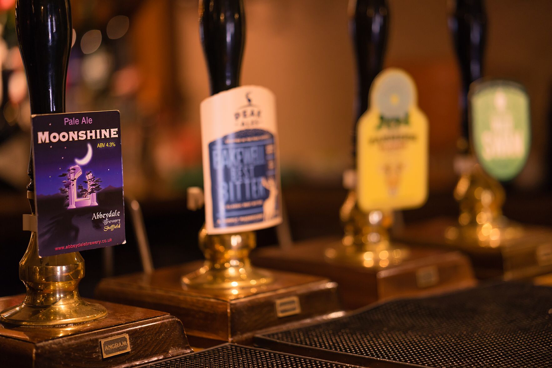 Een bar met meerdere bierkraan aansluitingen, waaronder een met de tekst 'Pale Ale MOONSHINE' en een andere met 'BEER'.