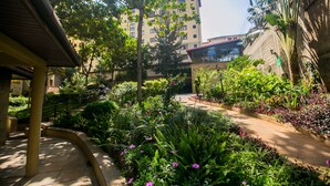A courtyard with a curved pathway, surrounded by lush greenery and flowering plants. - Serene Valley Apartments & Spa (Nairobi)