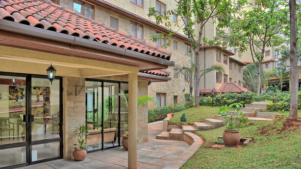 A hotel with a covered entrance, outdoor seating, and a landscaped garden. - Serene Valley Apartments & Spa (Nairobi)