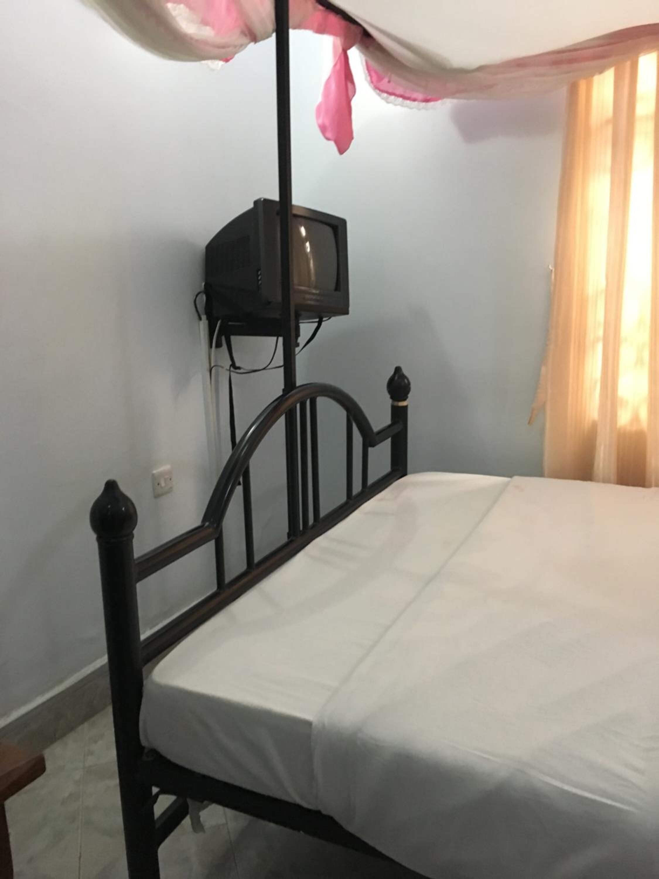 Una cama individual con colchón blanco y estructura de metal negro en una habitación con paredes azul claro.
