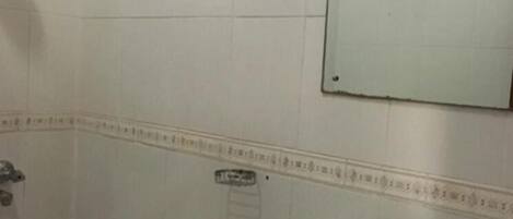 A bathroom with a white sink, a shower, and a mirror with a decorative frame.