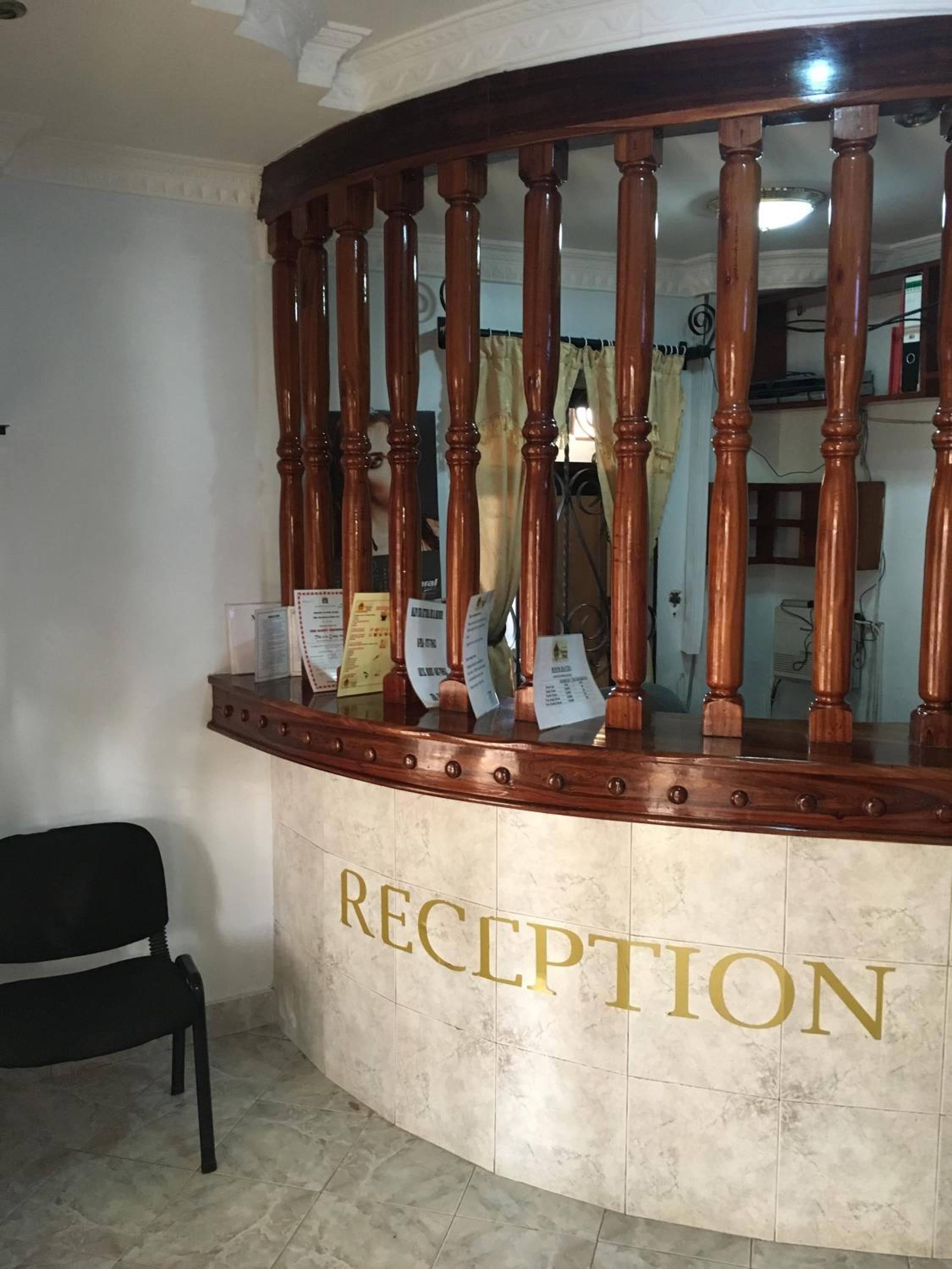 A reception desk with a marble counter and a wooden railing.