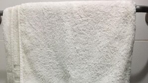 A white towel hanging on a black towel bar in a bathroom with patterned tiles.