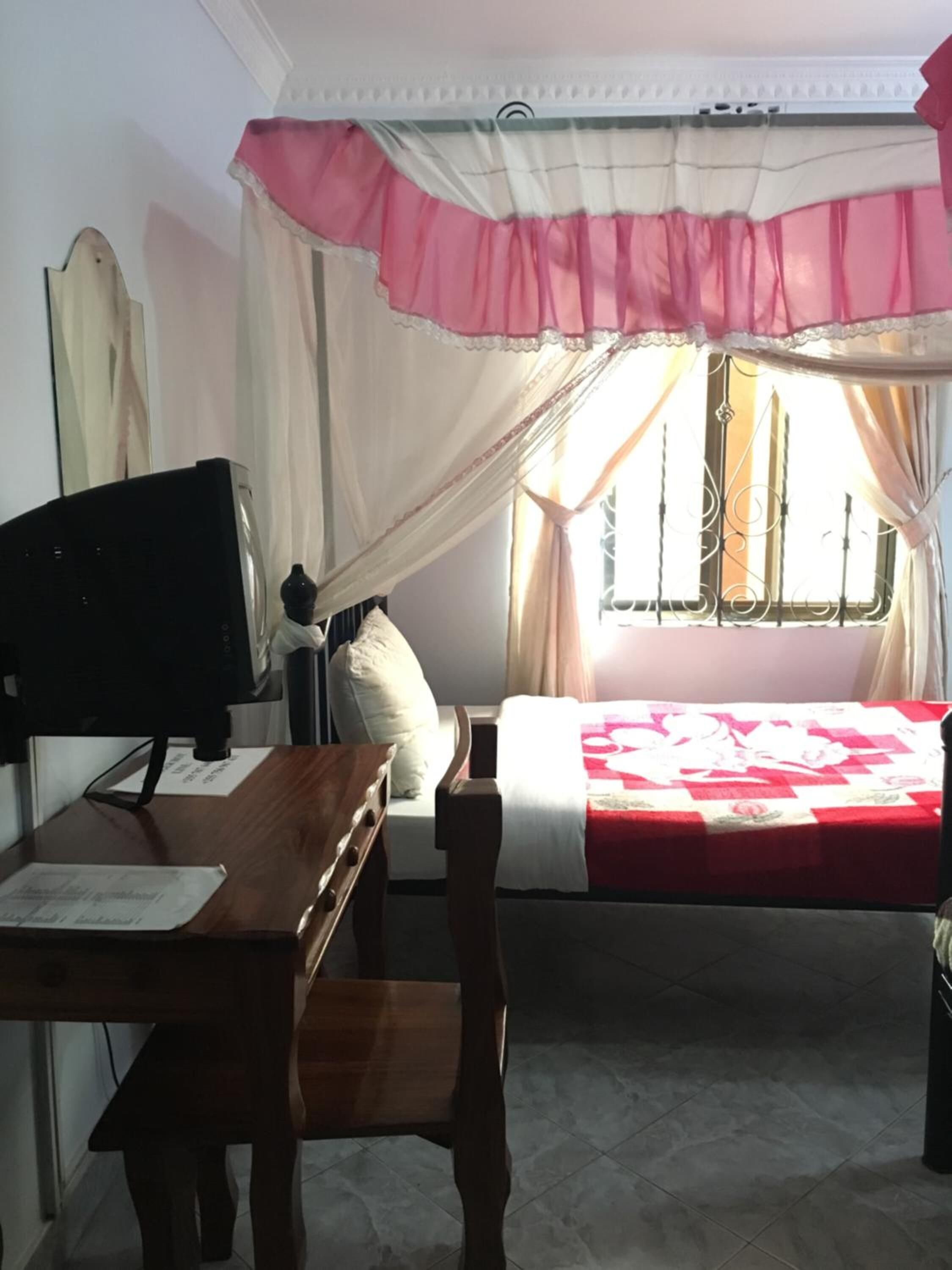 A bedroom with a bed, a desk, and a chair.
