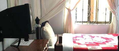 A bedroom with a bed, a desk, and a chair.