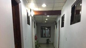 A hallway with tiled flooring, potted plants, and framed pictures on the walls.