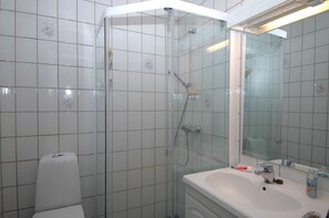 Un baño con ducha de vidrio, inodoro y lavabo con espejo.
