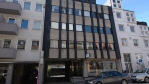 A multi-story building with a modern facade, featuring large windows and a ground-level entrance with a visible storefront. - Solferie Holiday Apt. Kronprinsensgate (Kristiansand)