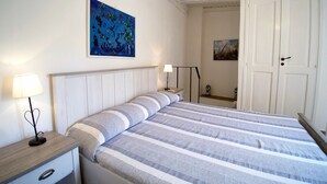 A bedroom with a bed, bedside tables, and artwork on the walls. - Casa Levante (Syracuse)