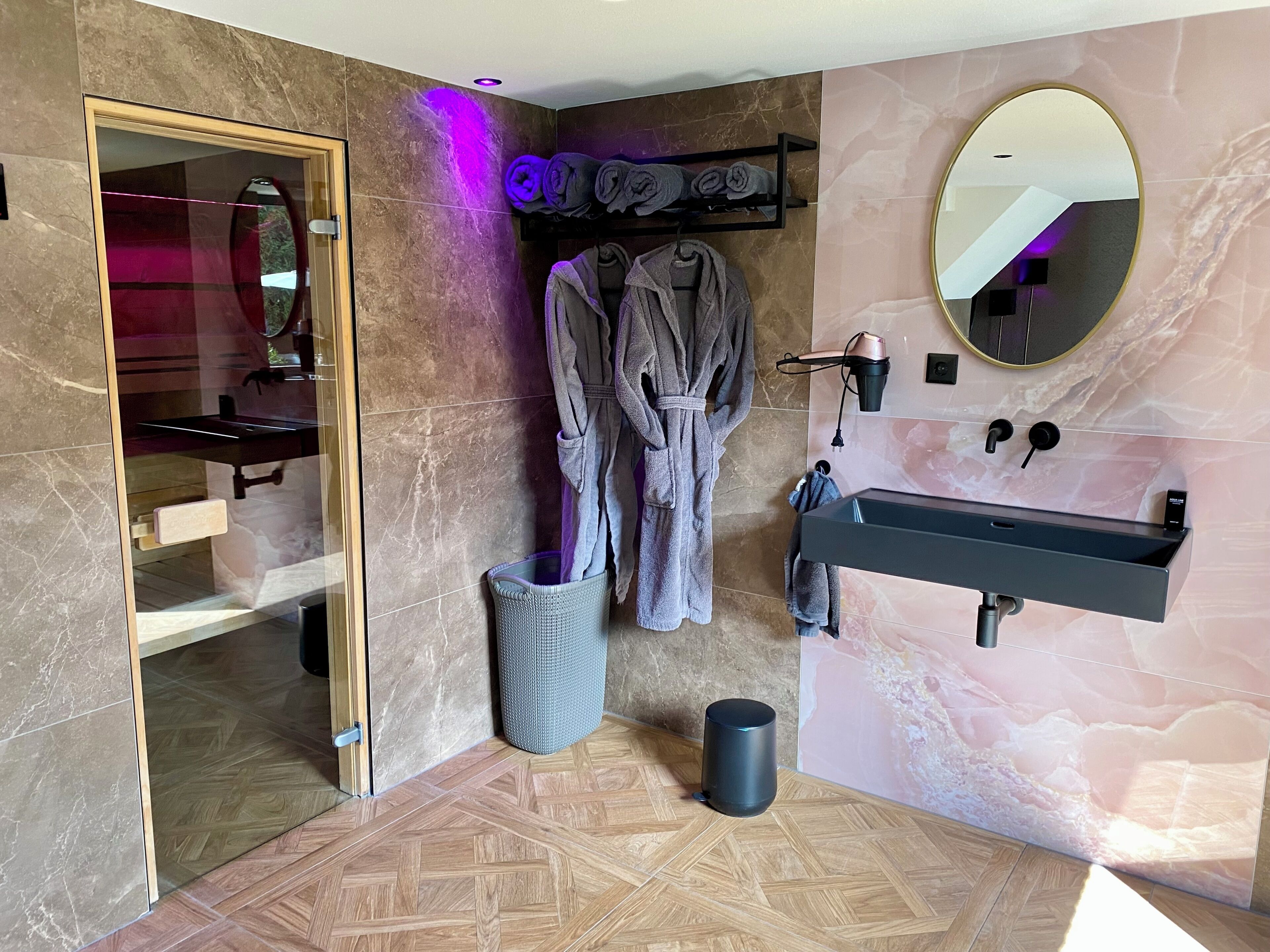 A modern bathroom with a vanity, a mirror, a towel rack, and a trash bin.