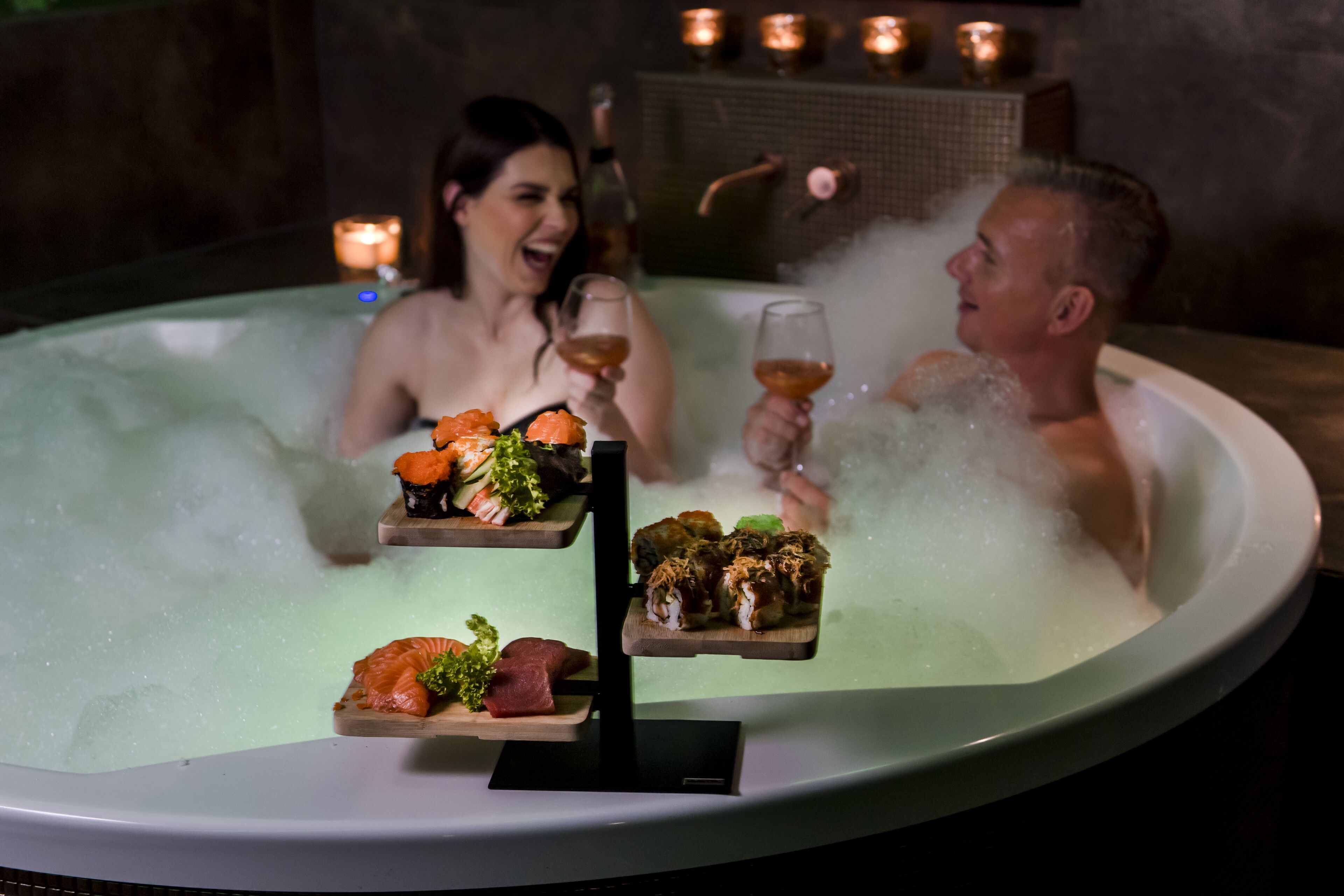 A hot tub with two people and a sushi platter.