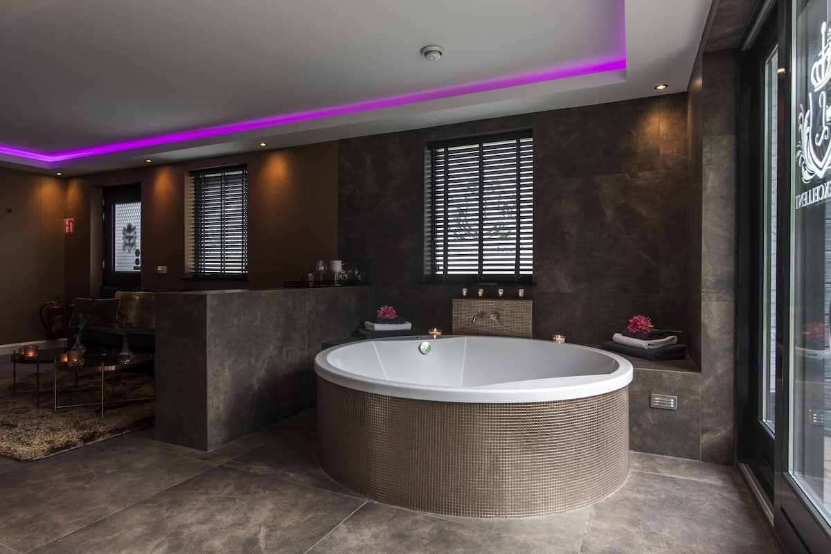 Une salle de bain moderne avec une grande baignoire îlot, une douche à parois de verre et un mur en marbre foncé.