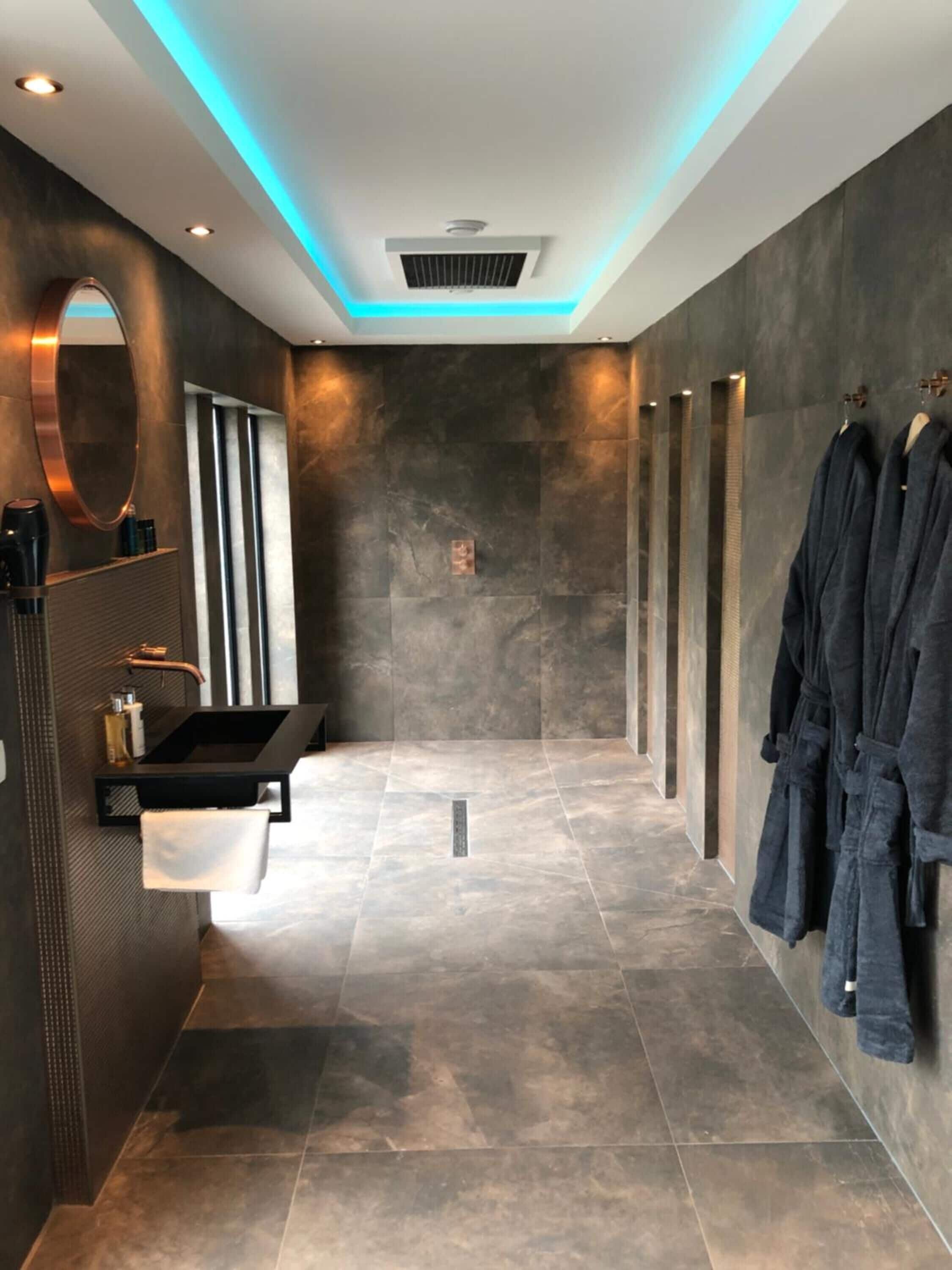 A modern bathroom with a black sink, a mirror, and a towel rack.
