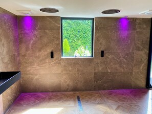 A modern bathroom with marble walls, a window with a view of greenery, and a wooden floor. - Luxexcellent Exclusieve B&B (Nuland)