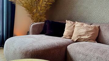 A living room with a sofa, a potted plant, and three lit candles.