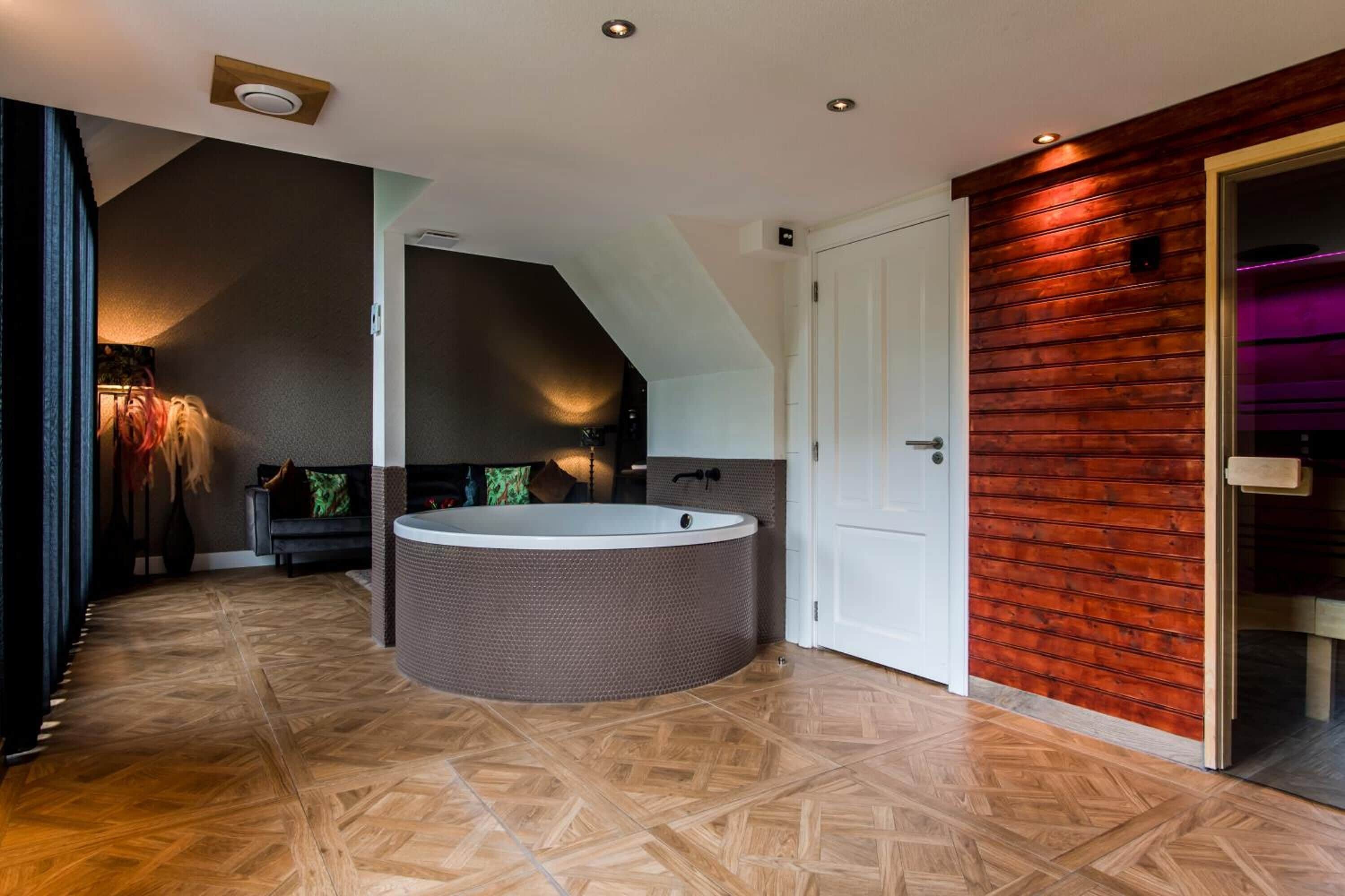 Un baño moderno con una bañera independiente, piso de madera y techo inclinado.