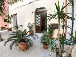 Un patio con plantas en macetas y la entrada de un edificio.