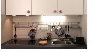 Cozinha com duas pias, bancadas de aço inoxidável e armários suspensos.