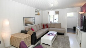 A modern living room with a sectional sofa, a coffee table, and a television on a cabinet. - Solferie Holiday Home - Svartefjell (Kristiansand)