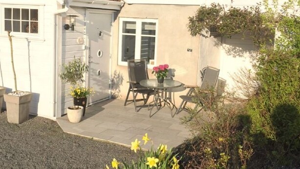 A house with a patio, a small garden, and a table with chairs. - Solferie Holiday Home - Svartefjell (Kristiansand)