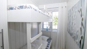 Dormitorio con literas, paredes blancas y una ventana.