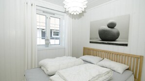A bedroom with a bed, white curtains, a window, and a painting on the wall. - Solferie Holiday Home - Svartefjell (Kristiansand)