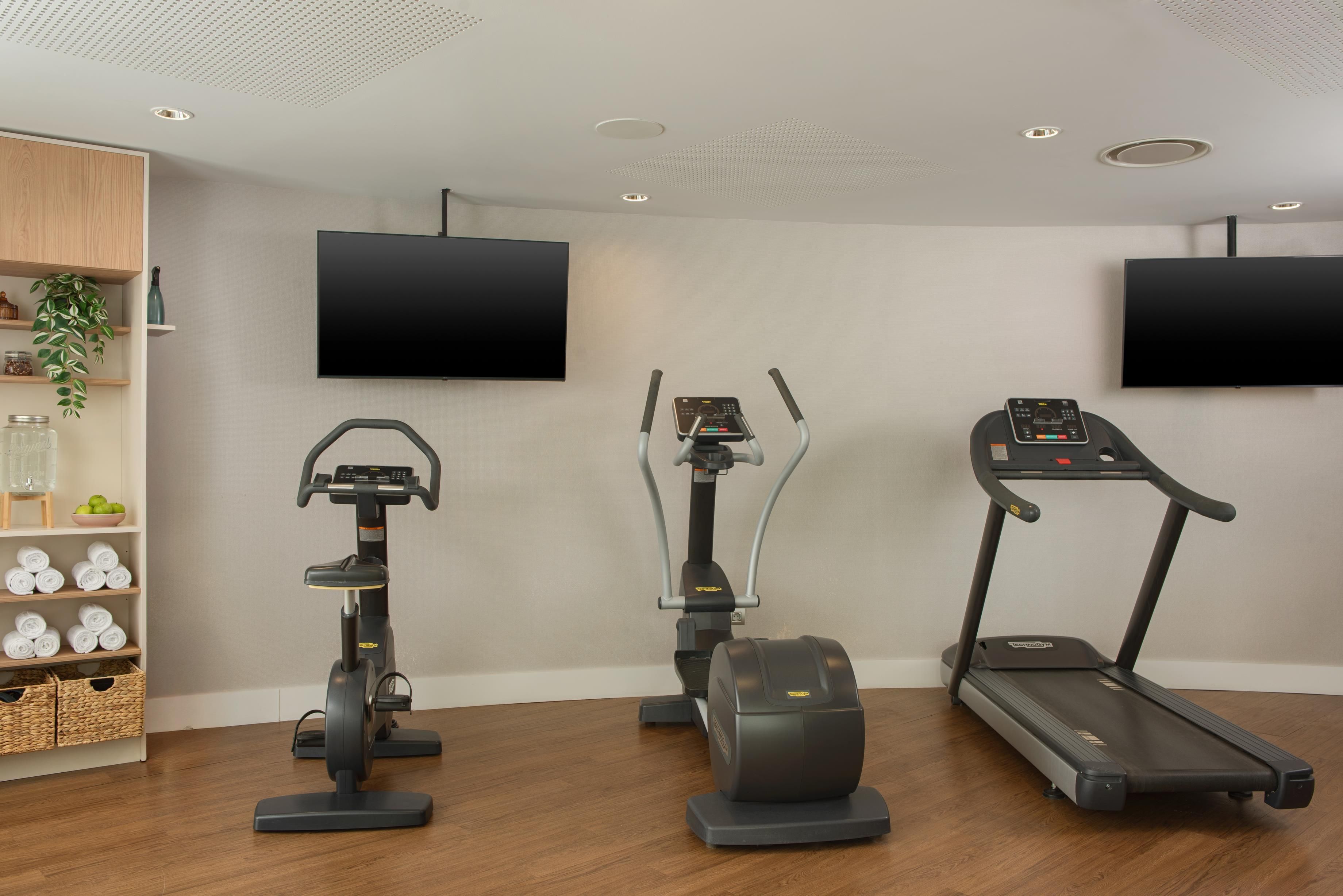 A home gym with an elliptical, a stationary bike, and a treadmill.