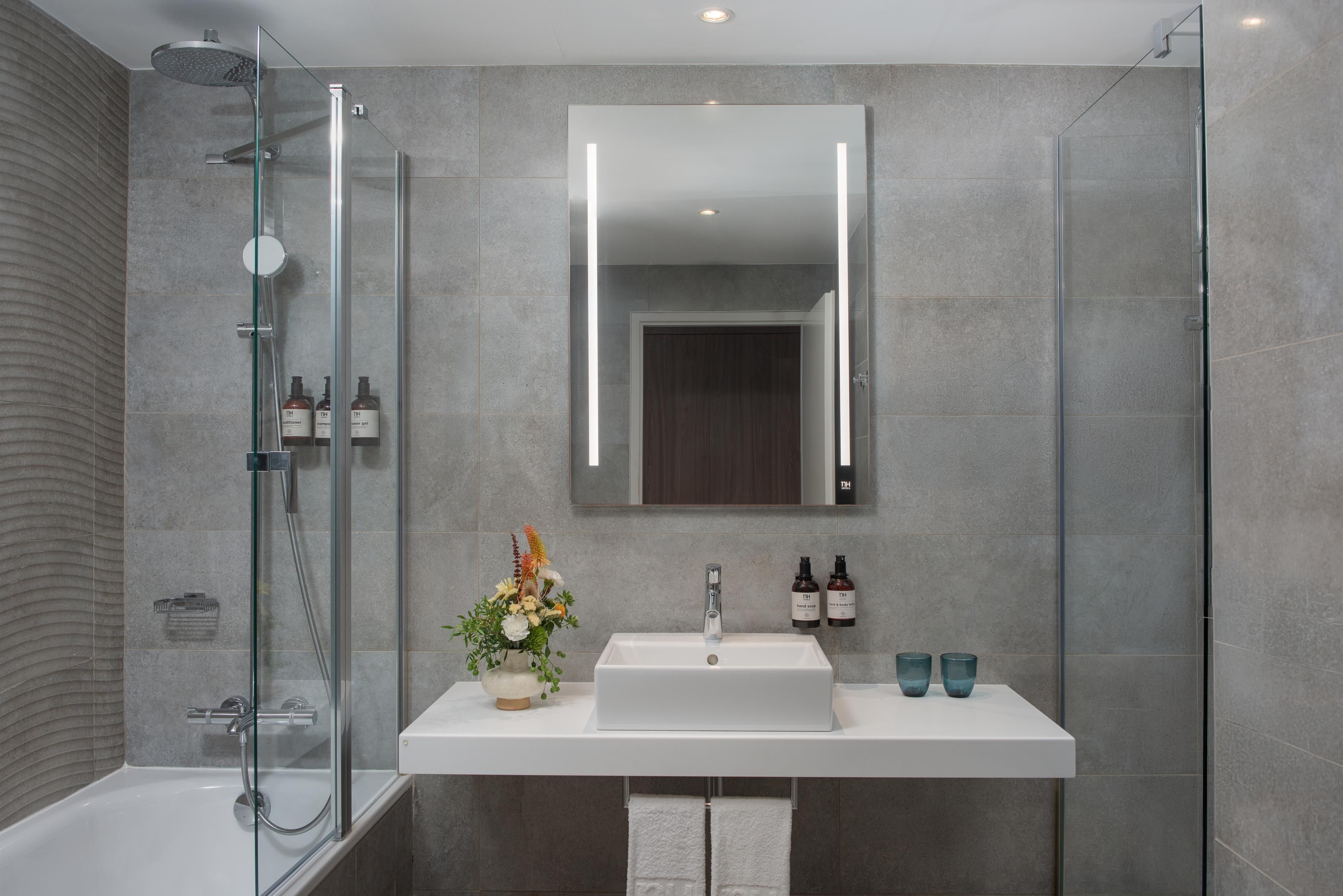 A modern bathroom with a glass-enclosed shower, a white sink, and a mirror above it.