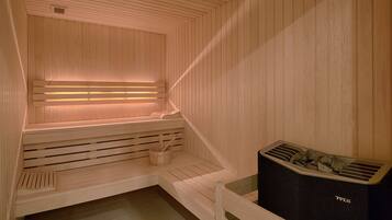 A sauna with wooden benches, a bench with a towel, and a stone heater.