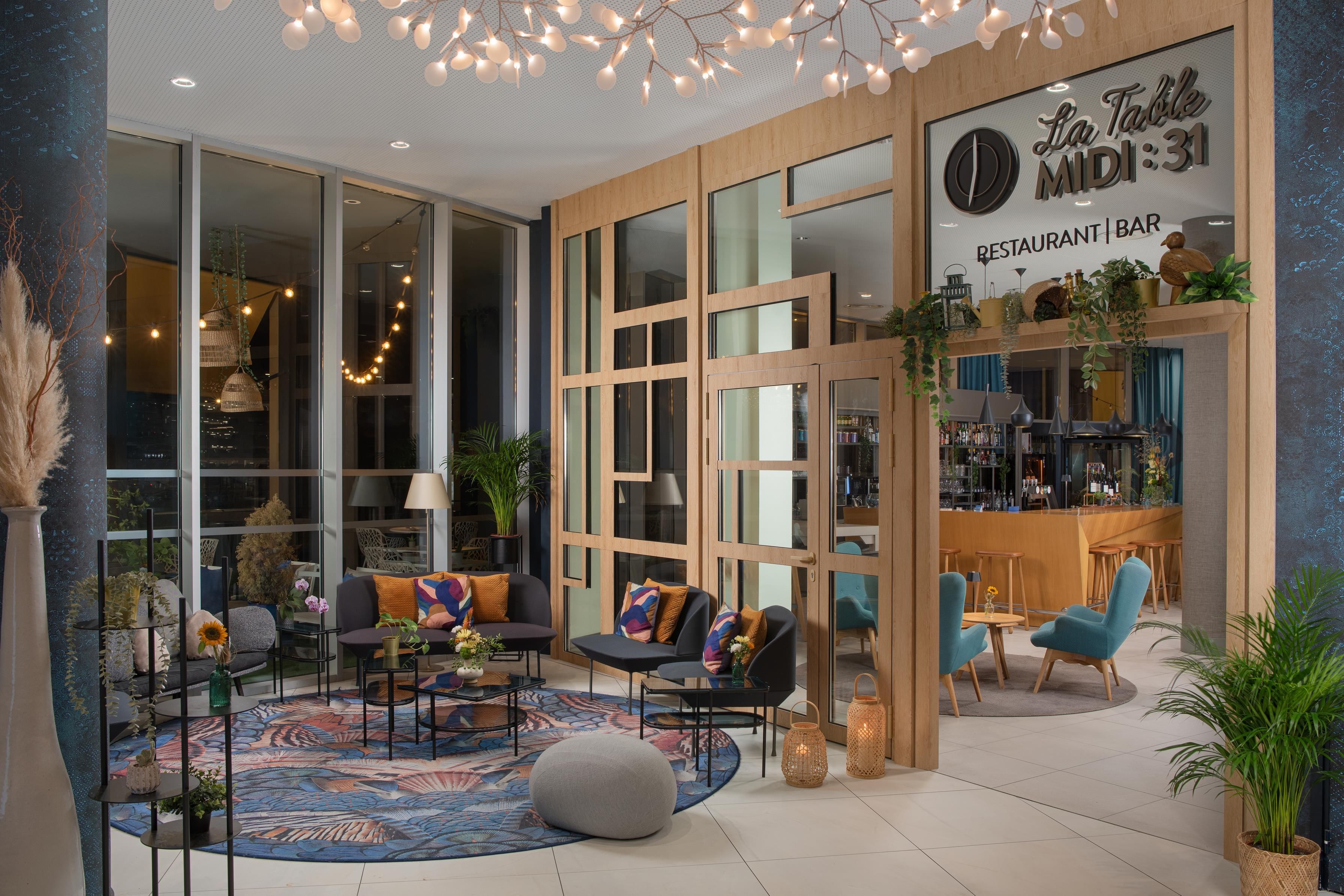 A modern interior with a bar area, seating, and large windows.