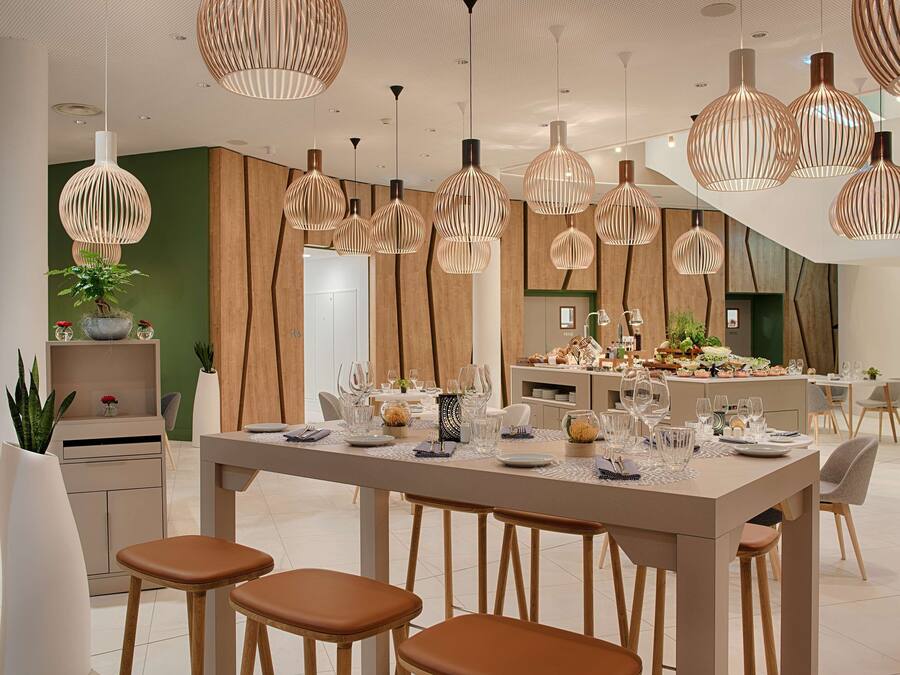 Un comedor moderno con una mesa larga dispuesta para varios invitados, rodeada de sillas y taburetes de madera.