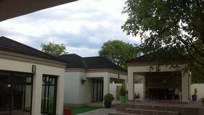 A courtyard with a covered seating area, potted plants, and a brick pathway. - Lediba Guest lodge (Maun)
