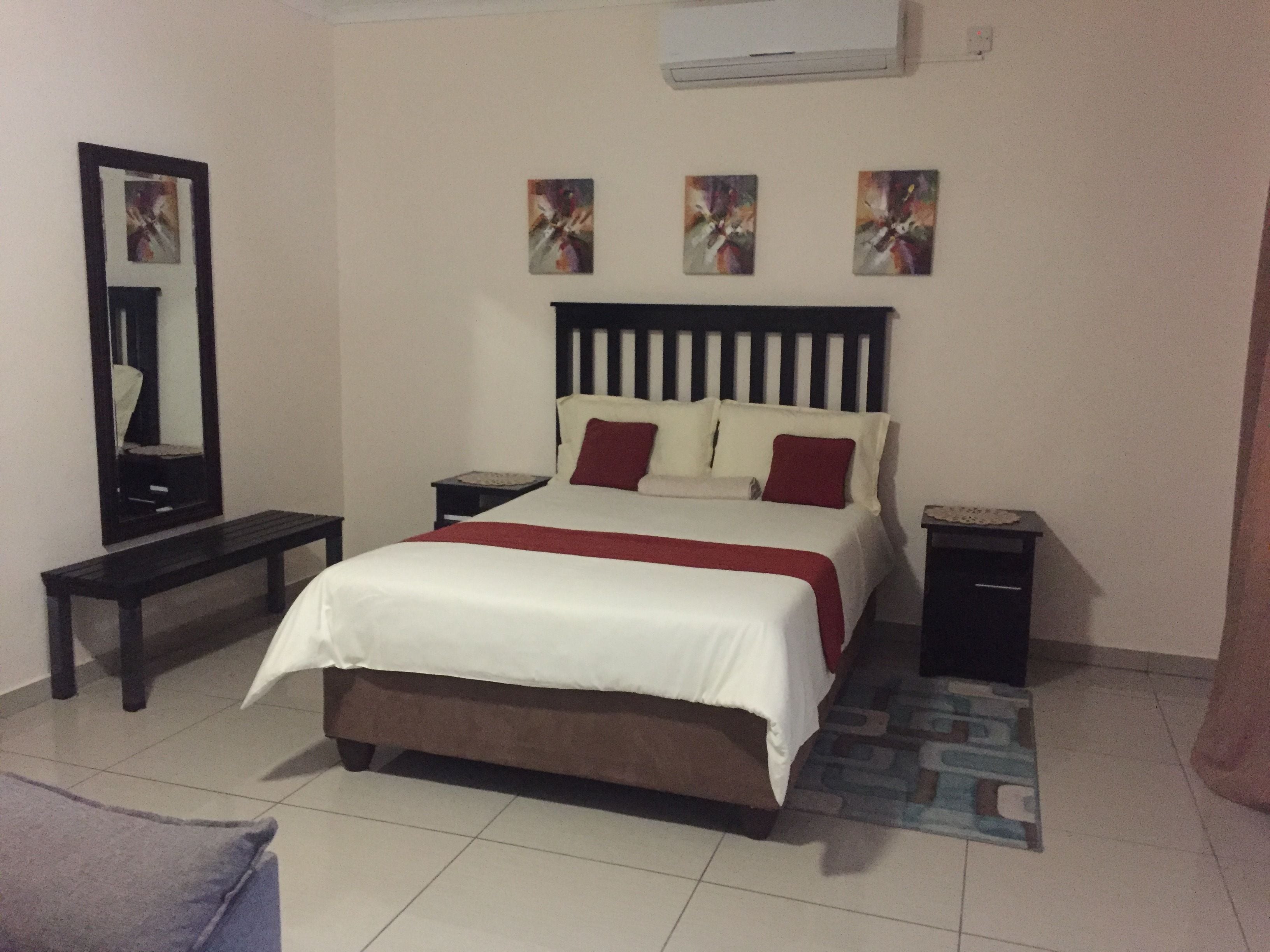 A bedroom with a bed, bedside tables, a mirror, and artwork on the wall.