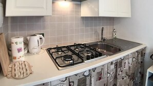 Une cuisine équipée d’une cuisinière à gaz, d’une bouilloire et d’un évier.