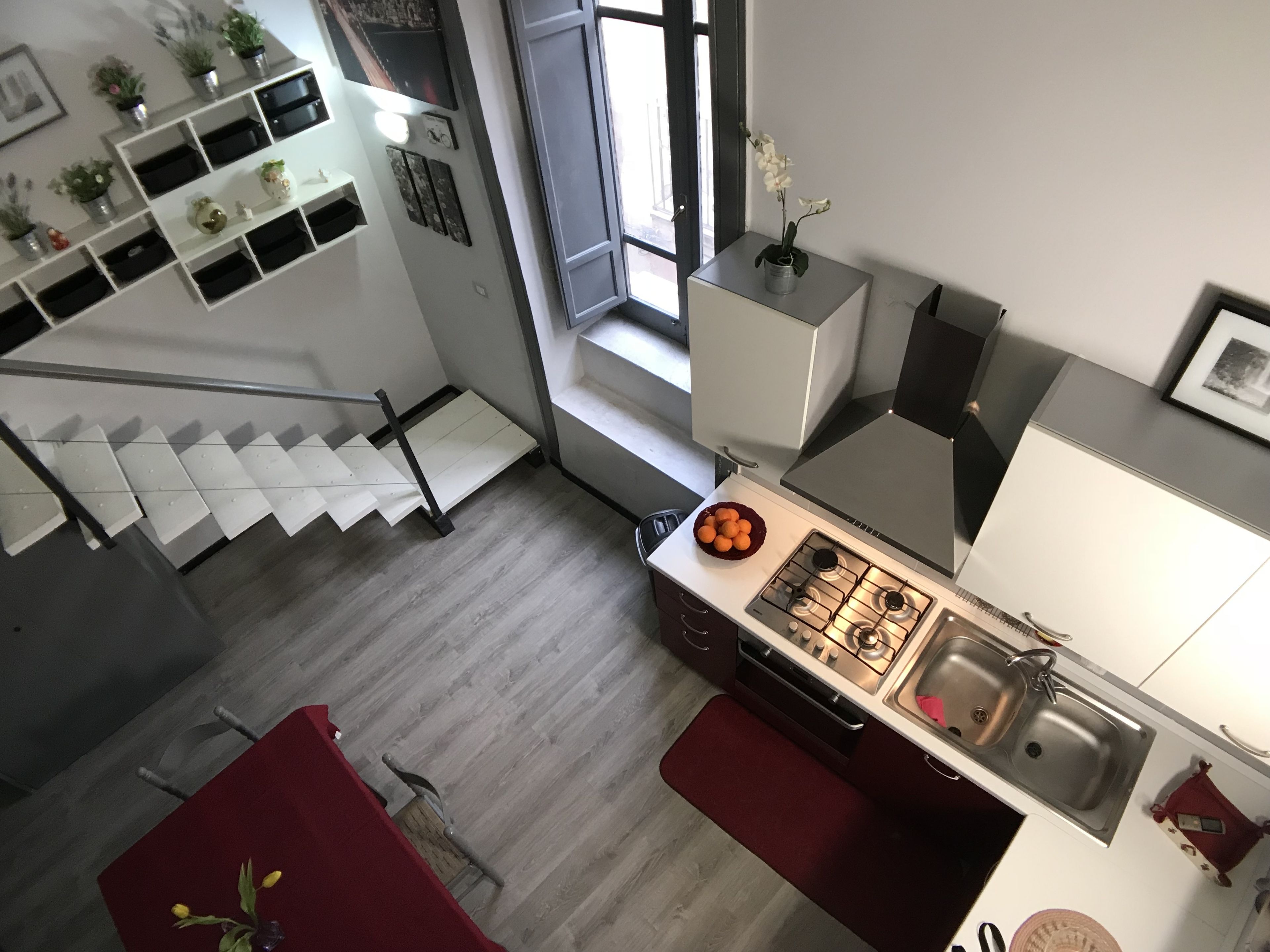 Une cuisine moderne équipée d’une cuisinière à gaz, d’un évier et d’un coin repas avec une table et un banc rouges.
