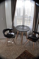 Una habitación con una mesa redonda y dos sillas, una alfombra estampada y vistas a un balcón con barandilla.