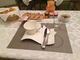 Una mesa de desayuno con pan, mantequilla, mermelada y una jarra de jugo.